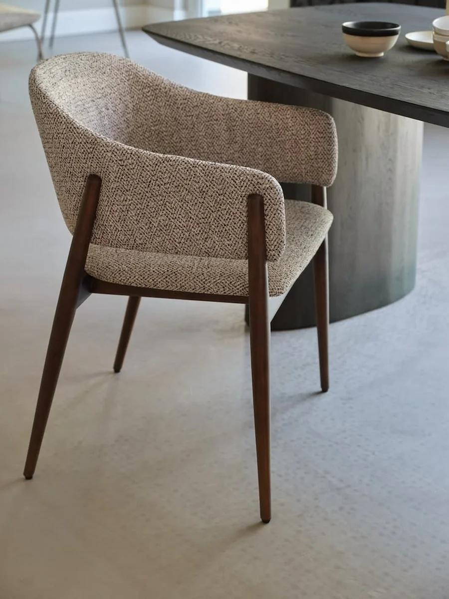 CGI packshot of a beige boucle dining armchair at a dark table